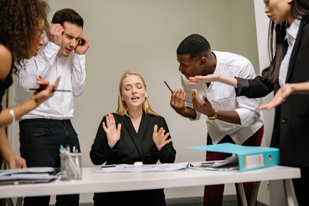 Diverse employees engaged in a heated discussion at a workplace meeting, showcasing stress and tension.